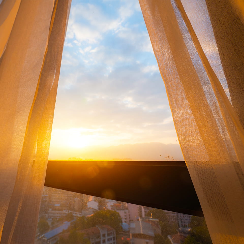 Window and curtains with sunrise on horizon